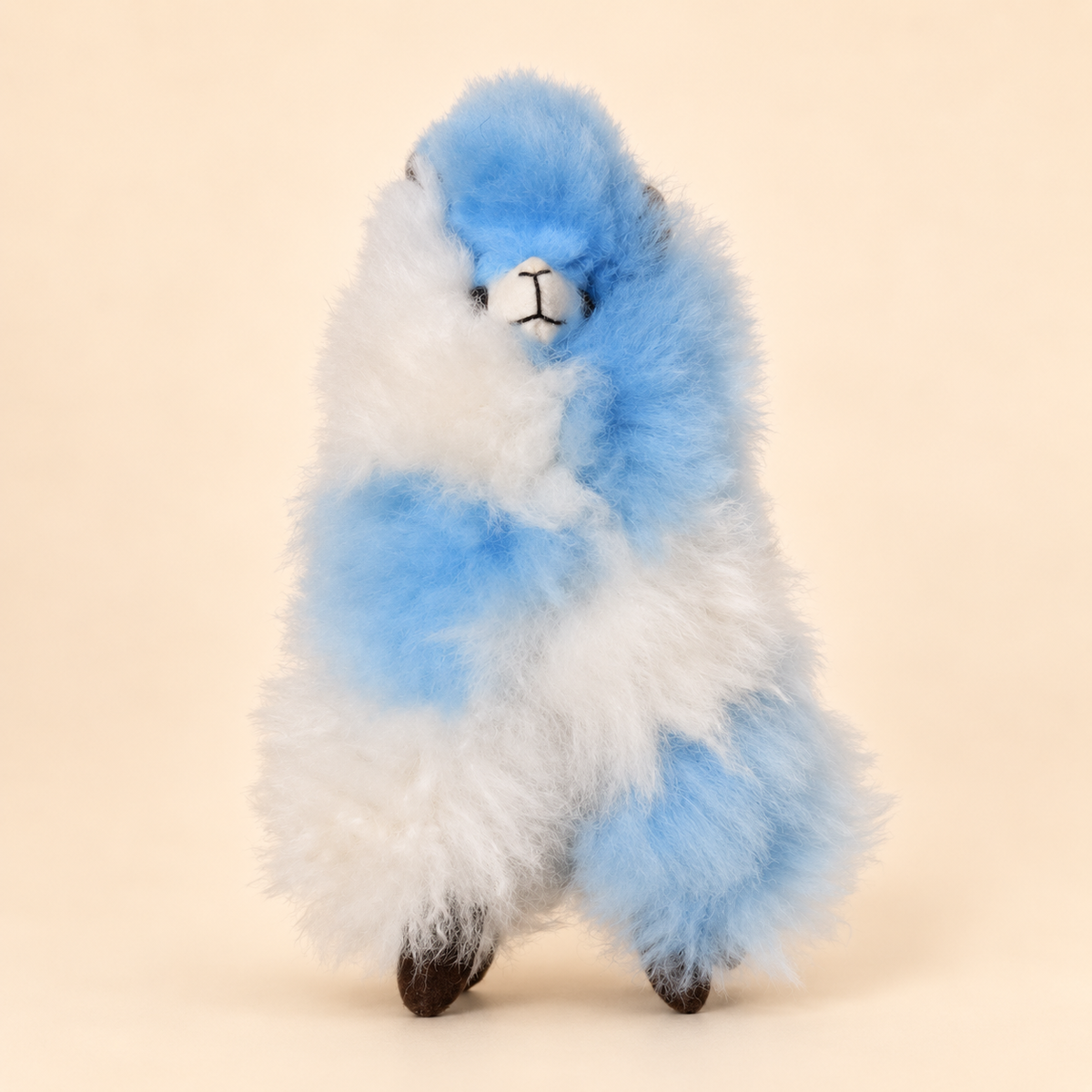 Peluche alpaga 20 cm bleu et blanc, vue de face sur fond crème