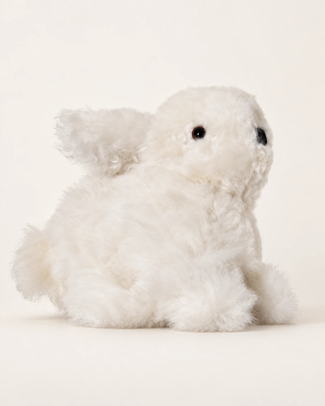 Peluche lapin blanche en laine d’alpaga de 15 cm, vue de trois quarts sur fond crème.