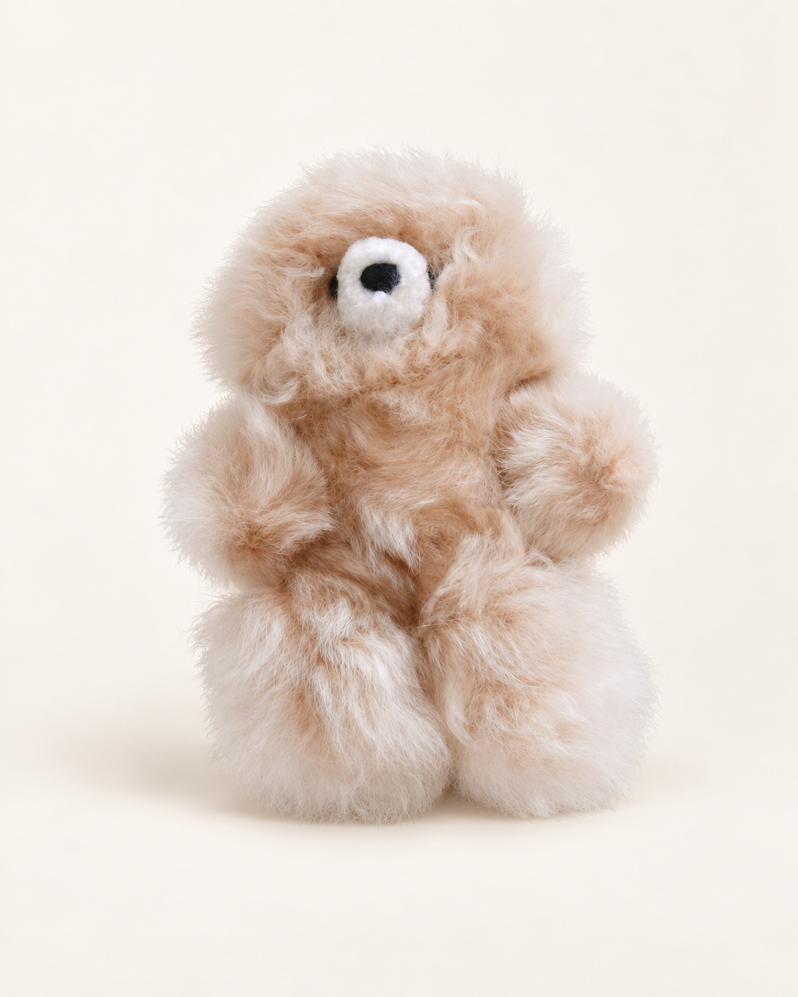 Peluche ours beige clair en laine d’alpaga de 17 cm, avec museau blanc et nez noir, sur fond crème.