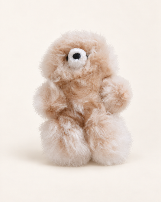 Peluche ours beige clair en laine d’alpaga de 17 cm, avec museau blanc et nez noir, sur fond crème.
