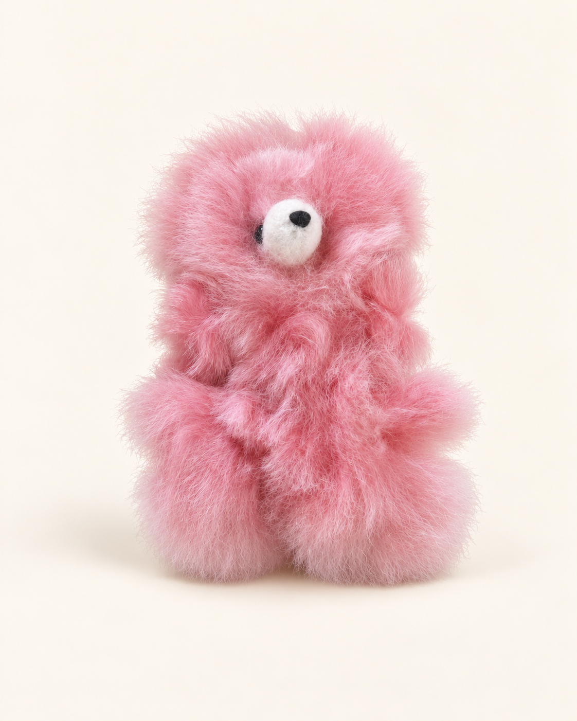 Petite peluche ours rose en laine d’alpaga de 10 cm, avec museau blanc et nez noir, sur fond crème.