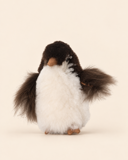Peluche pingouin en laine d’alpaga de 15 cm, blanche et brun foncé, sur fond crème